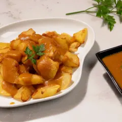 Patatas bravas crujientes cubiertas con salsa picante y perejil fresco. Un plato español delicioso.