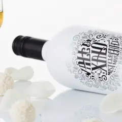 Botella de mistela que es, con copa de vino y dulces.