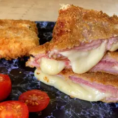 San Jacobo crujiente con queso fundido y jamón, acompañado de tomates cherry.