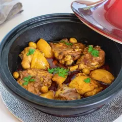 Tajín de pollo con patatas y aceitunas, decorado con perejil fresco. Un plato aromático listo para servir.