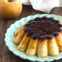 Delicioso pudin de manzana con cobertura oscura, servido en plato turquesa.