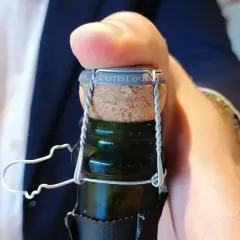 Dedo presionando el corcho de una botella de cava "CASTELL D'OR". Aprende como abrir una botella de vino espumoso.