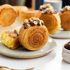 Deliciosos new york rolls cubiertos de chocolate y avellanas, uno abierto revela un cremoso relleno.