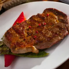Jugoso entrecot a la plancha, servido con pimientos verdes y un toque de pimientos rojos.