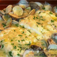 Merluza en salsa verde con almejas, un plato casero de Loli Domínguez, con perejil picado y una salsa cremosa.