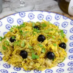 Delicioso bacalao a bras, un plato tradicional con patatas finas, huevo y aceitunas negras, espolvoreado con perejil fresco.