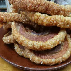 Crujientes torreznos en freidora de aire, apilados en un plato de barro. Un aperitivo irresistible.