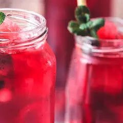 Refrescante agua de jamaica con hielo, menta y trozos de sandía en vasos rústicos.