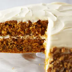 Delicioso pastel de zanahoria con glaseado cremoso y nueces picadas en los bordes.