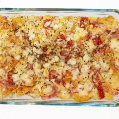 Nachos con queso recién horneados, cubiertos con trozos de tocino y pimientos rojos.