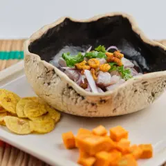 Delicioso ceviche de corvina fresco, servido en un cuenco rústico con patacones y cubos de camote.