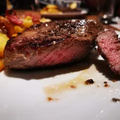 Un jugoso entrecot de ternera a la parrilla, servido con patatas doradas y un tenedor listo para degustar.
