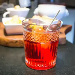 Cóctel rojo vibrante, una mezcla de vermut rojo y blanco, con guarnición de limón.