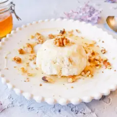 Delicioso mel y mató con nueces, servido en un plato blanco con borde festoneado.