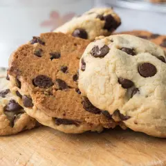 Galletas con pepitas de chocolate recién horneadas, apiladas sobre una tabla de madera.
