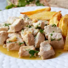 Sabroso lomo al ajillo en trozos, bañado en aceite y ajo, con patatas fritas doradas al lado.