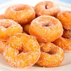 Montón de rosquillas caseras de toda la vida, doradas y espolvoreadas con azúcar, listas para disfrutar.
