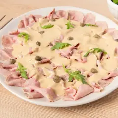 Delicioso vitello tonnato con finas lonchas de ternera, salsa cremosa, alcaparras y rúcula. Un plato italiano clásico.