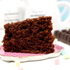 Un trozo de bizcocho de avena de chocolate, esponjoso y delicioso, servido en un plato rosa.