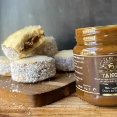 Alfajores cubiertos de coco y un frasco de dulce de leche Tango, listos para disfrutar.
