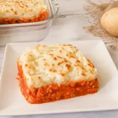 Un delicioso pastel de patata y carne, cubierto con puré de patatas dorado y servido en un plato blanco.