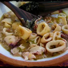 Calamares en salsa, un plato casero con trozos tiernos y tentáculos, servido en un cuenco de barro.