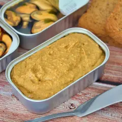 Un paté de mejillones cremoso en lata, junto a mejillones en conserva y tostadas.