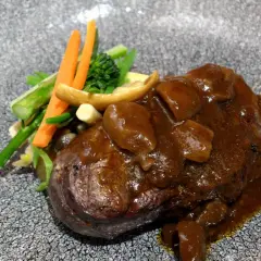 Delicioso solomillo en salsa de la abuela, acompañado de verduras frescas y champiñones. Un plato que evoca recuerdos y sabores caseros.