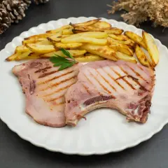 Dos chuletas de sajonia a la parrilla con patatas fritas y perejil. Un plato delicioso y listo para disfrutar.