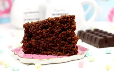 Un trozo de bizcocho de avena de chocolate, esponjoso y delicioso, servido en un plato rosa.