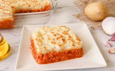 Un delicioso pastel de patata y carne, cubierto con puré de patatas dorado y servido en un plato blanco.