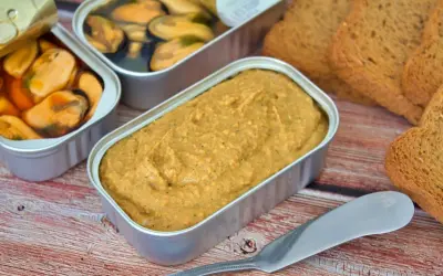 Un paté de mejillones cremoso en lata, junto a mejillones en conserva y tostadas.
