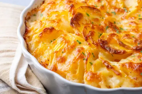 Patatas gratinadas con queso cremoso y trocitos de bacon crujiente, un plato reconfortante y delicioso.