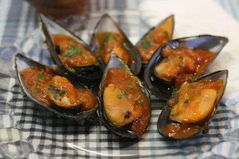 Mejillones en salsa como en los bares, servidos en sus conchas y espolvoreados con perejil fresco.