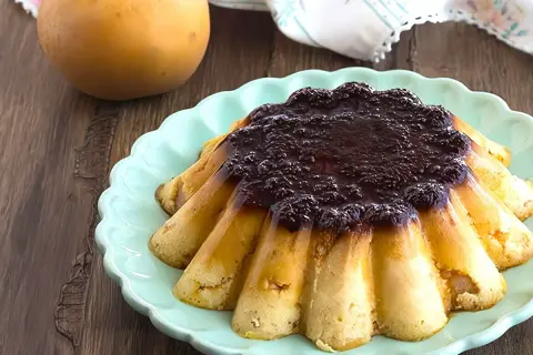 Delicioso pudin de manzana con cobertura oscura, servido en plato turquesa.