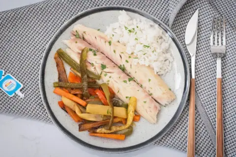 Deliciosa lubina a la sal, servida con arroz blanco y verduras asadas. Un plato saludable y lleno de sabor.