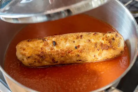 Rollo de bonito dorado y crujiente nadando en una salsa de tomate casera, listo para ser servido.