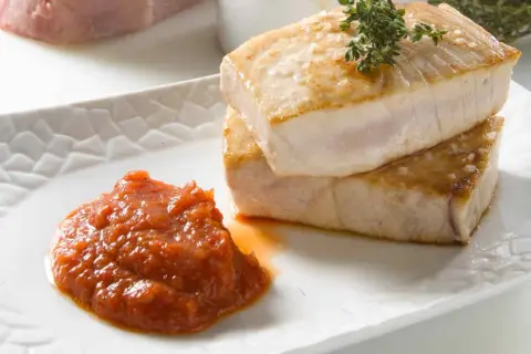 Dos jugosos medallones de atún a la plancha, con sal marina y romero, acompañados de una salsa de tomate casera.