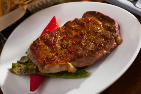 Jugoso entrecot a la plancha, servido con pimientos verdes y un toque de pimientos rojos.