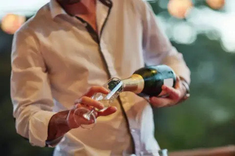 Un hombre sirve cava en una copa. El cava es un vino espumoso español, perfecto para celebraciones.
