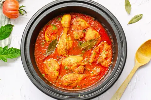 Sabroso pollo con tomate cocinado a fuego lento, con hojas de laurel y perejil picado.