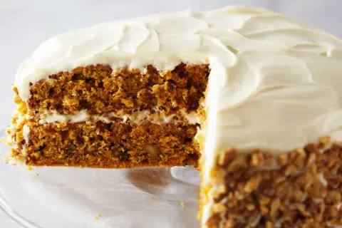 Delicioso pastel de zanahoria con glaseado cremoso y nueces picadas en los bordes.