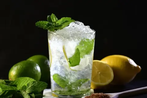 Un refrescante mojito con hielo picado, menta y rodajas de limón. Ingredientes para una mojito receta perfecta.
