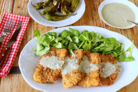 Escalopines al cabrales crujientes, servidos con ensalada verde y pimientos asados. ¡Un plato delicioso!