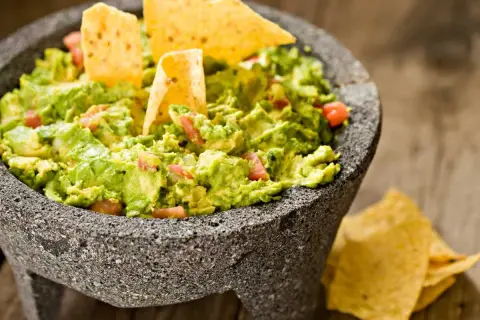 Guacamole fresco en molcajete, listo para disfrutar. Una deliciosa guacamole receta con totopos.