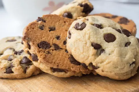 Galletas con pepitas de chocolate recién horneadas, apiladas sobre una tabla de madera.