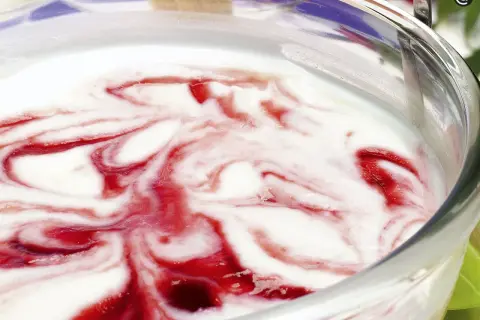 Delicioso helado de queso con remolinos de fresa en un tazón de vidrio.
