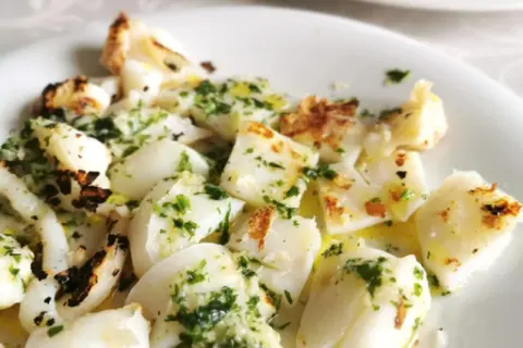 Sabrosa sepia a la plancha, cortada en trozos y aderezada con perejil fresco y aceite de oliva.