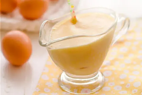 Crema pastelera lista para usar, con huevos frescos al fondo. ¡Perfecta para tu próxima receta!