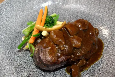 Delicioso solomillo en salsa de la abuela, acompañado de verduras frescas y champiñones. Un plato que evoca recuerdos y sabores caseros.